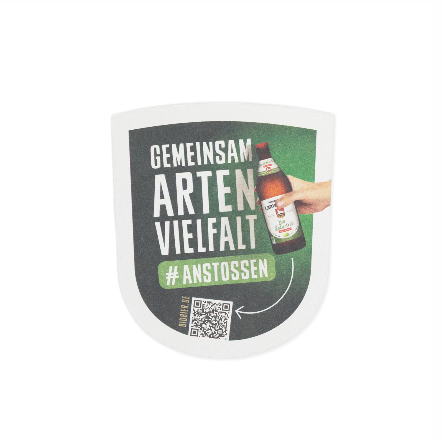Wappenförmiger Bierdeckel auf weißem Hintergrund. Die obere Hälfte zeigt auf dunkelgrünem Hintergrund den weißen Text „GEMEINSAM ARTEN VIELFALT" und das Hashtag „#ANSTOSSEN". Daneben eine fotografierte Hand, die eine dunkelbraune Neumarkter Lammsbräu-Bierflasche mit hellem Etikett hält. Unten links befindet sich ein schwarzer QR-Code mit der Aufschrift „BIOBIER.DE".