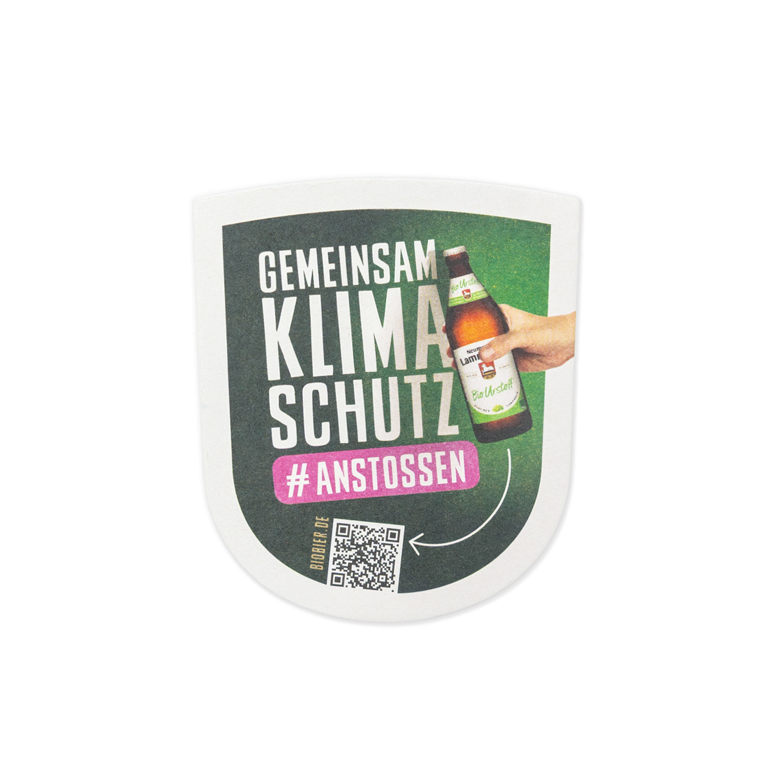 Wappenförmiger Bierdeckel auf weißem Hintergrund. Die obere Hälfte zeigt auf dunkelgrünem Hintergrund den weißen Text „GEMEINSAM KLIMASCHUTZ" und das Hashtag „#ANSTOSSEN". Daneben eine fotografierte Hand, die eine dunkelbraune Neumarkter Lammsbräu-Bierflasche mit hellem Etikett hält. Unten links befindet sich ein schwarzer QR-Code mit der Aufschrift „BIOBIER.DE".