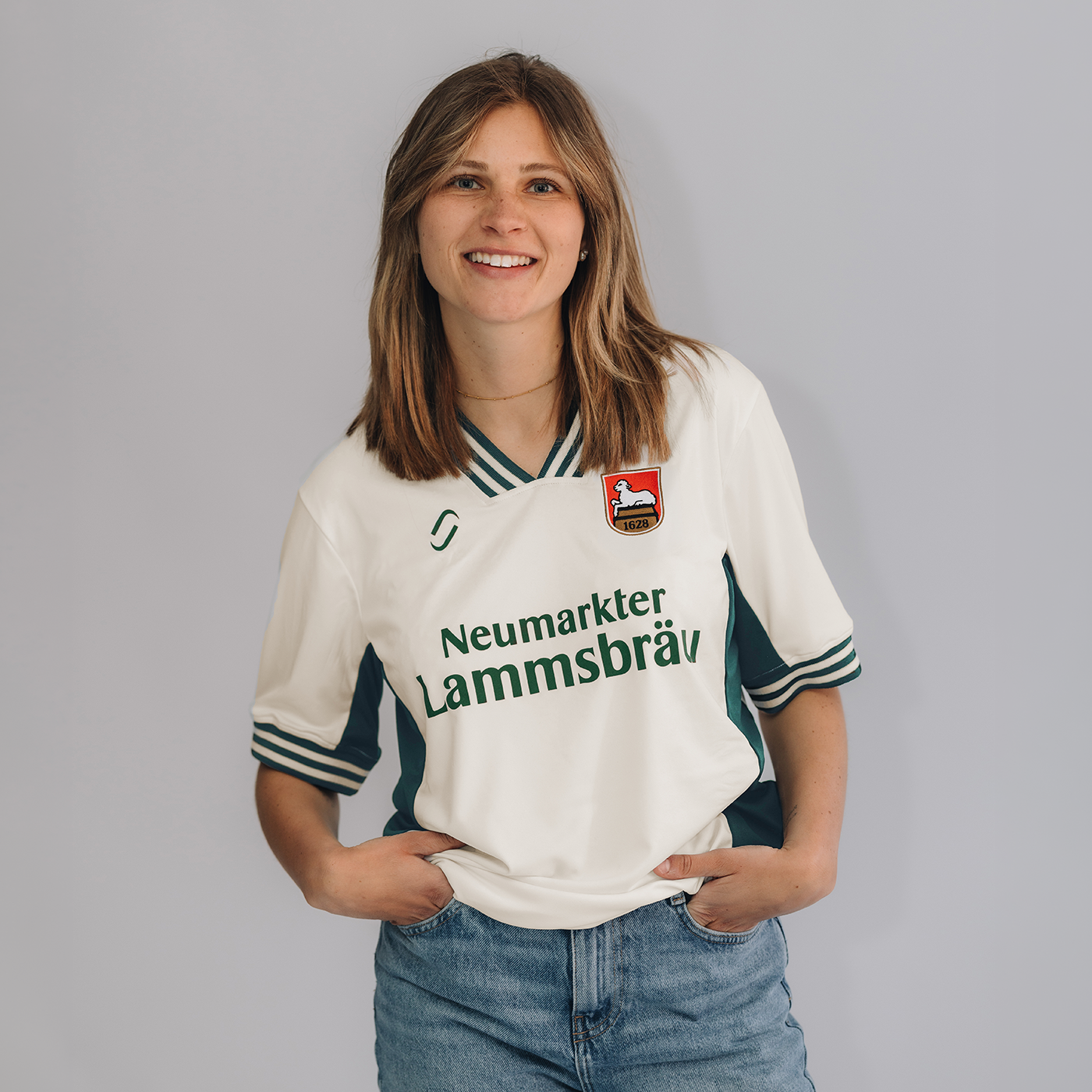 Ein weibliches Model trägt ein Retro-Fußballtrikot. Das Trikot ist im Farbton "elfenbein" und hat auf der Brust den Schriftzug "Neumarkter Lammsbräu". Außerdem sind das Logo von runamics und das Logo von Lammsbräu auf dem Trikot integriert.